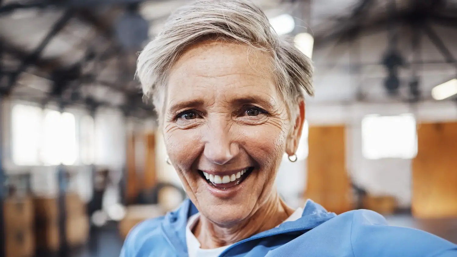 Senior kvinna i träningskläder ler mot kameran.