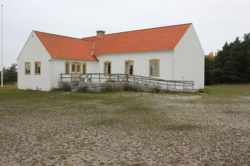 Ett vitt hus med bruna fönster och ett orange tak.