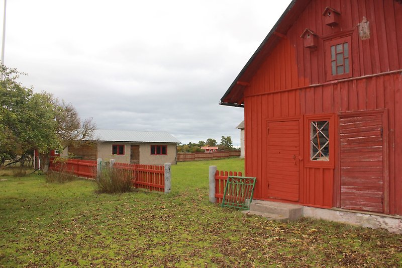 En röd träbyggnad med rött staket och två fågelbo.