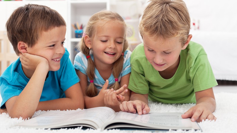 Tre barn läser i en bok