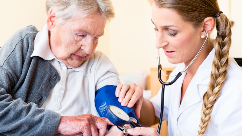 Sköterska som mäter blodtryck på en äldre kvinna