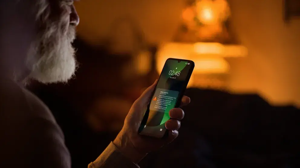 En man med skägg tittar på sin mobil där ett meddelande syns.