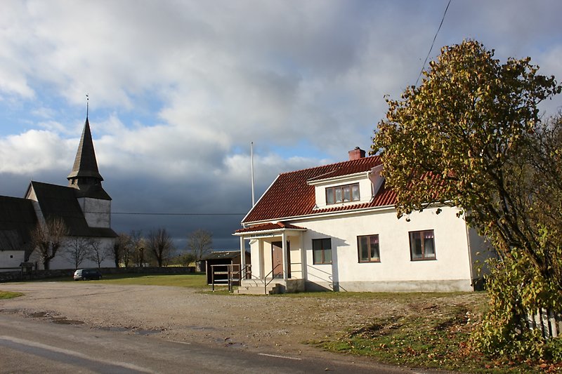 På höger sida om vägen finns det en bygdegård och längre bort syns det en kyrka.