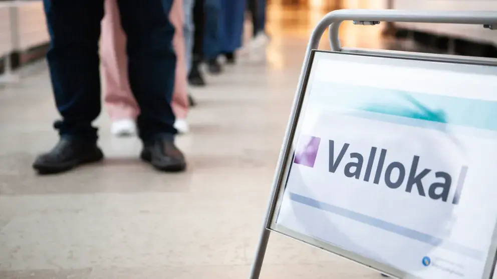 En skylt med texten "vallokal" och fötter som står i kö.